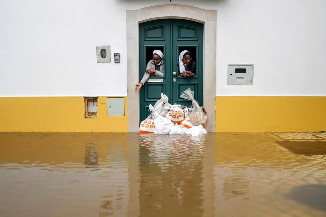 Two nuns looking out from a doorway protected by sandbags as floodwaters cover the street in Alcacer do Sal, south of Portugal, amid Storm Leonardo on Feb 4, 2026. A storm unleashing up to 35cm of rain in 24 hours battered the Iberian Peninsula, causing massive havoc.