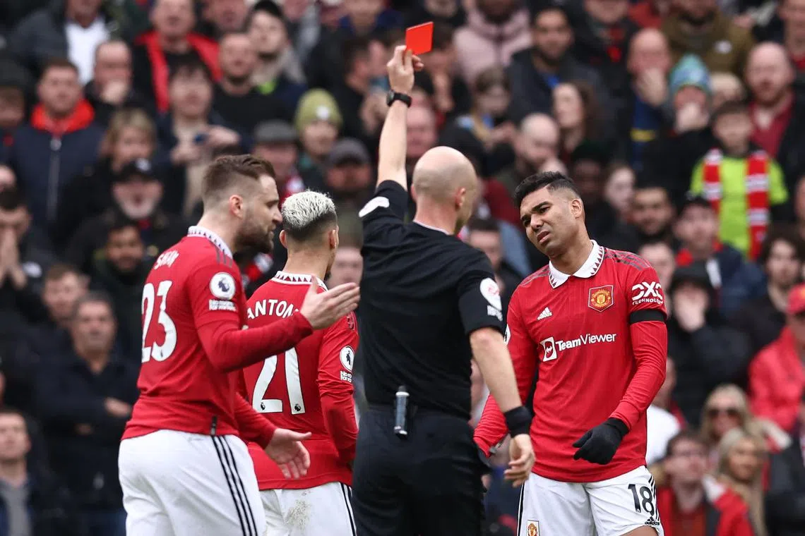 Manchester United's Brazilian midfielder Casemiro (right) is shown a red card by English referee Anthony Taylor.