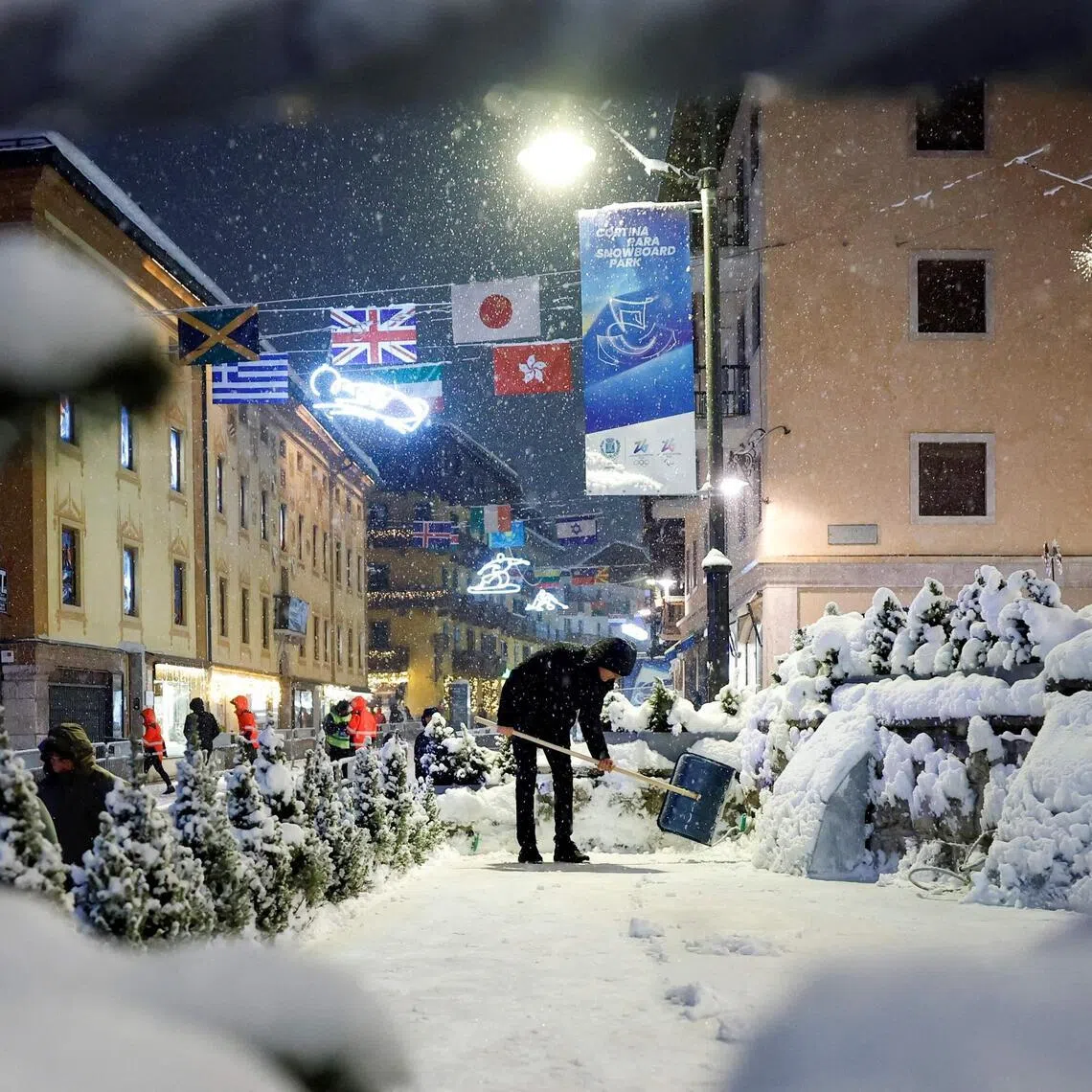 A business manager shovels snow outside a restaurant during snowfall in the main shopping area in Cortina d'Ampezzo.