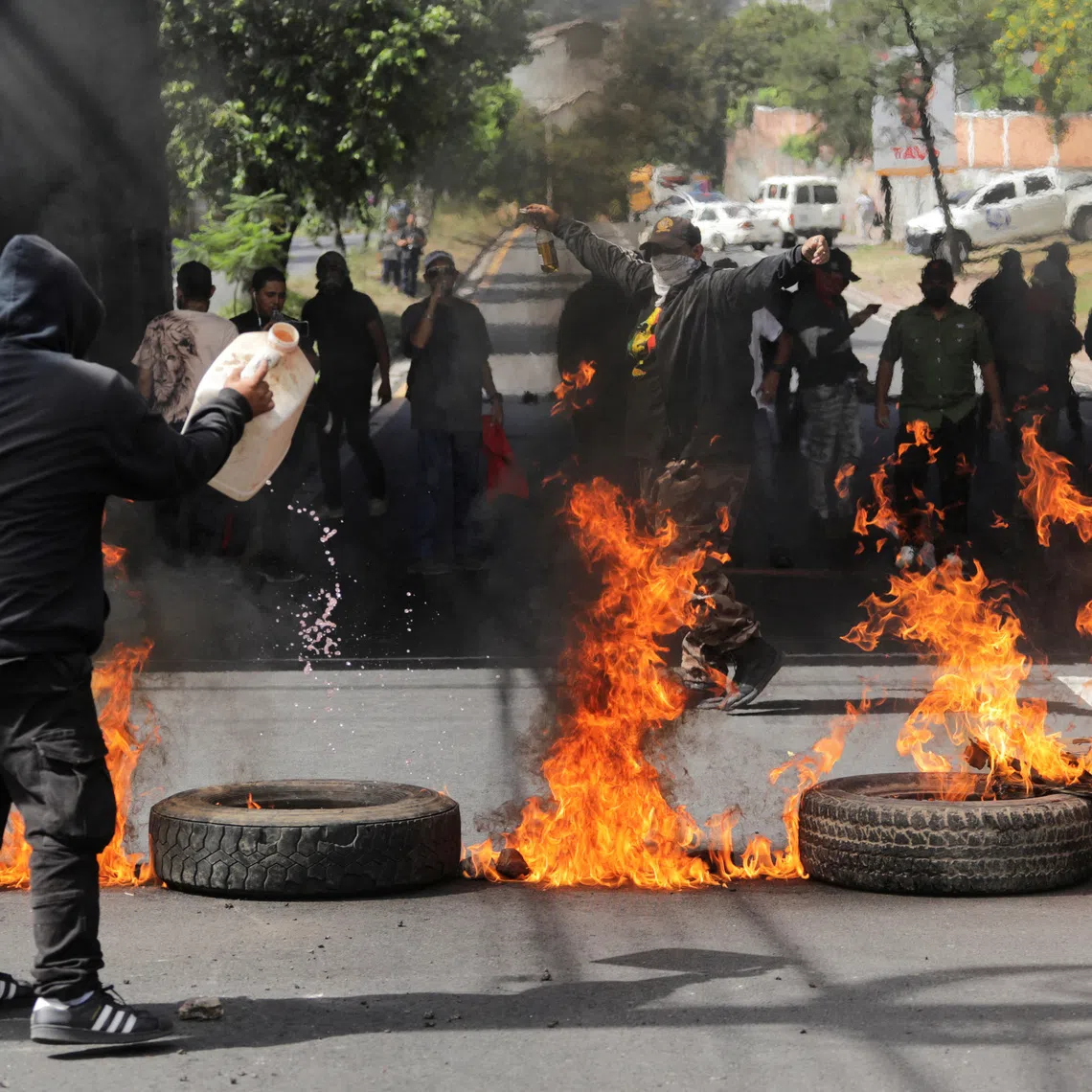 A demonstrator pours fuel on a barricade of burning tires as part of a protest nearly two weeks after the presidential election, as the vote remains stalled amid uncounted ballots, fraud accusations and electoral system failures, in Tegucigalpa, Honduras, December 15, 2025. REUTERS/Fredy Rodriguez