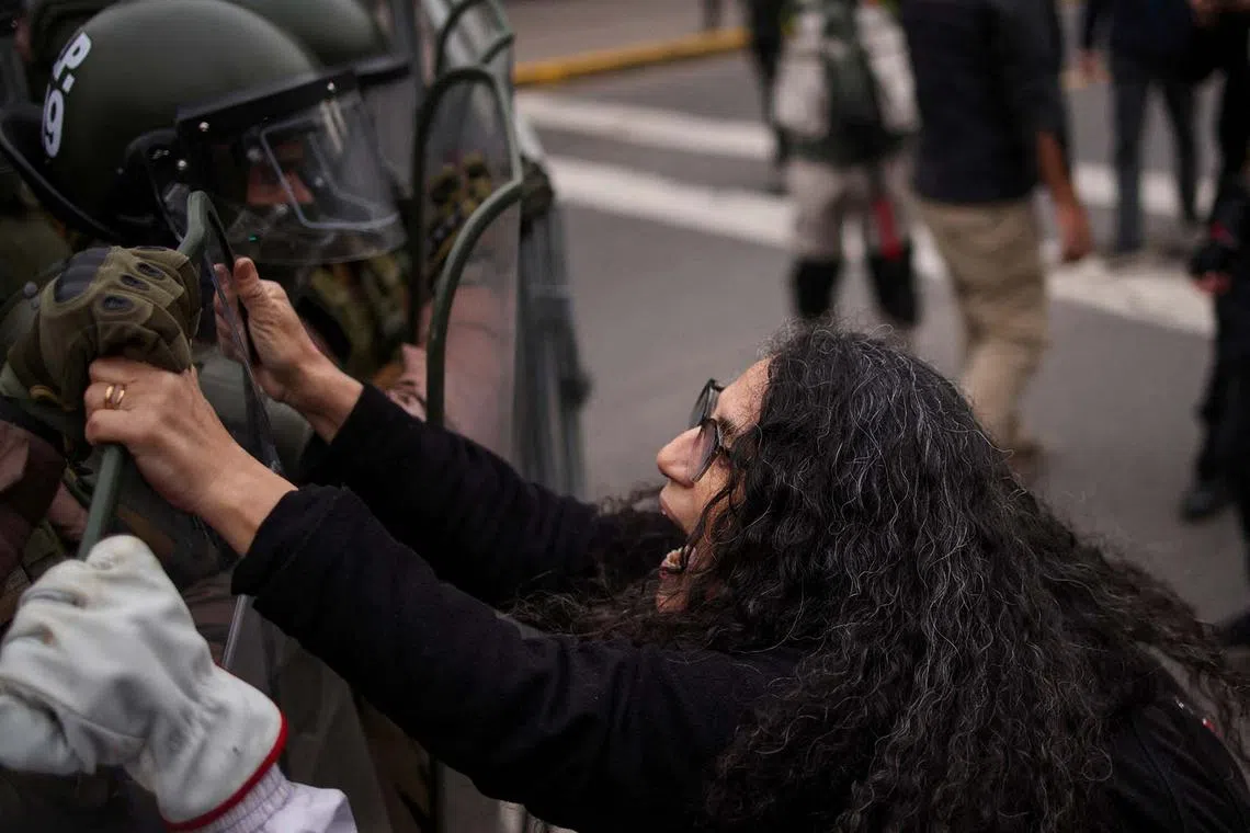 A demonstrator reacts in front of police during a rally-march ahead of the 50th anniversary of the 1973 Chilean military coup, in Santiago, Chile, Sept 10.