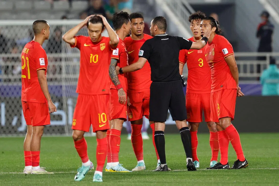 Saudi match referee Mohammed Khaled al-Hoish speaks with China's players during the match against Tajikistan.