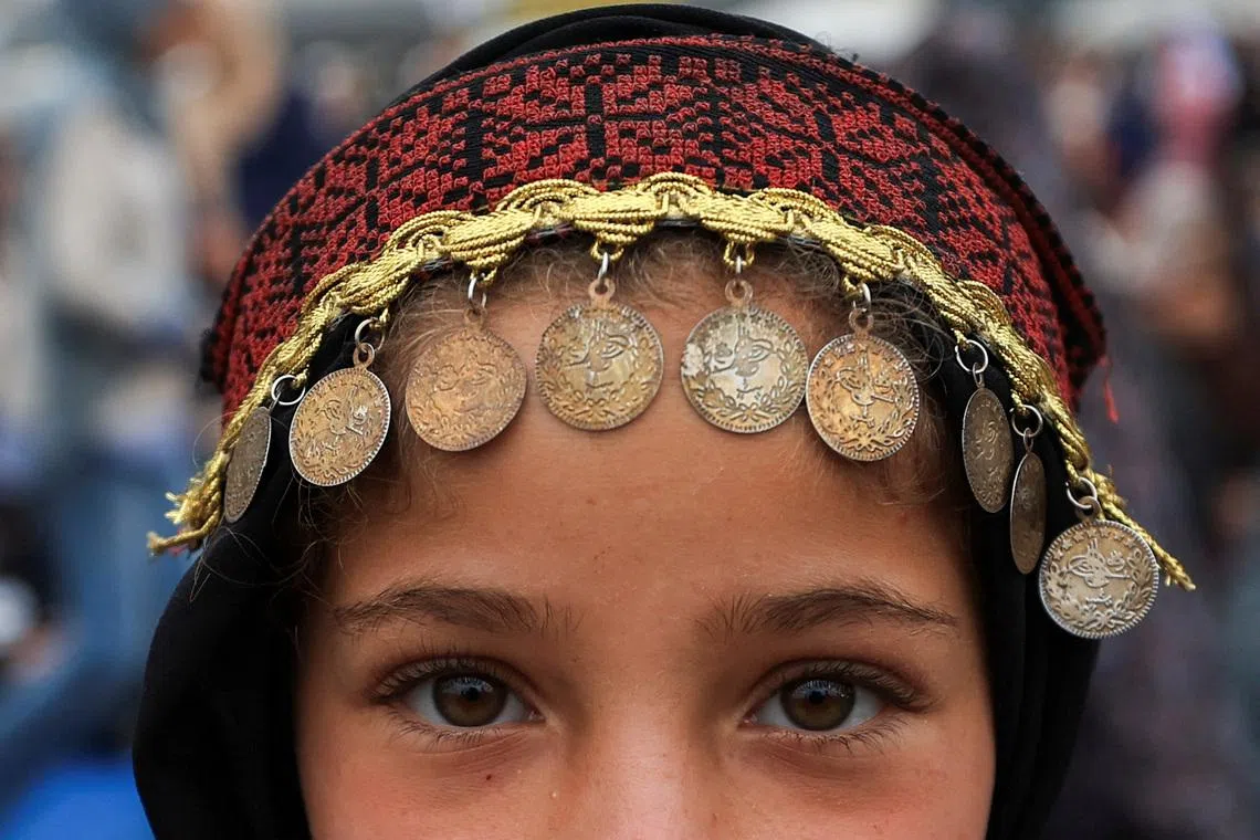 A Palestinian girl, wearing traditional headwear, posing for a photograph on Eid al-Adha, in Gaza City, on May 27, 2026. 