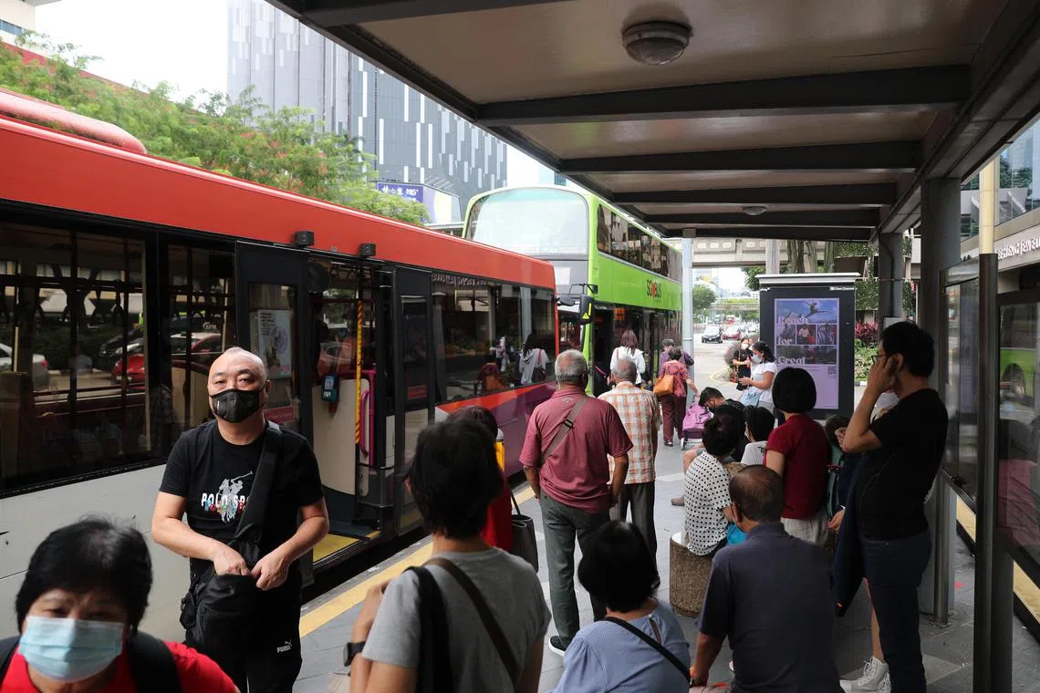 People waiting at the bus stop and some boarding the buses.