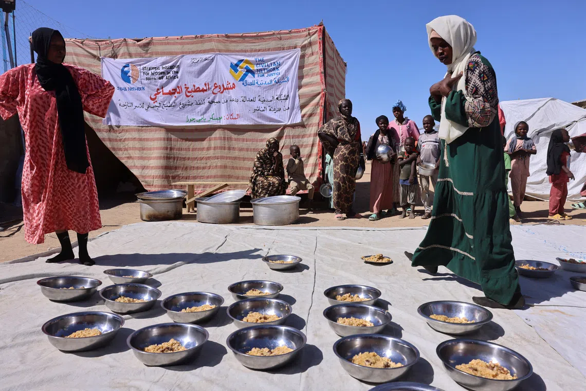Najwa Isa Adam (L), 32, a Sudanese refugee from al-Fashir, prepares bowls of pasta and meat for orphaned children and newly arriving refugee families using donated money at the Tine transit camp in eastern Chad, November 22, 2025. Najuwa says she was held captive at gunpoint by four Rapid Support Forces (RSF) fighters who repeatedly raped her amid the conflict with the Sudanese army. REUTERS/Amr Abdallah Dalsh