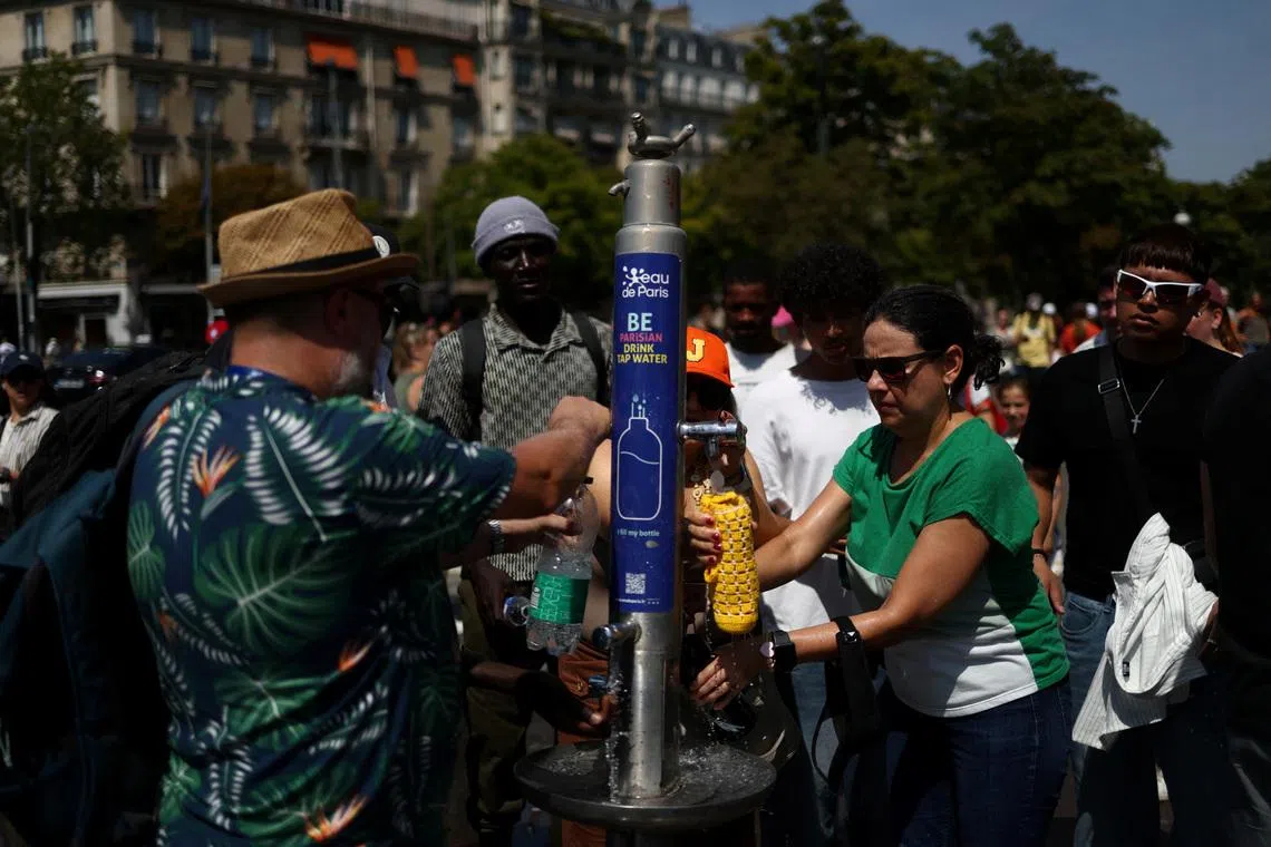 People refill water bottles from a public fountain near the Place du Trocadero in Paris on June 27.