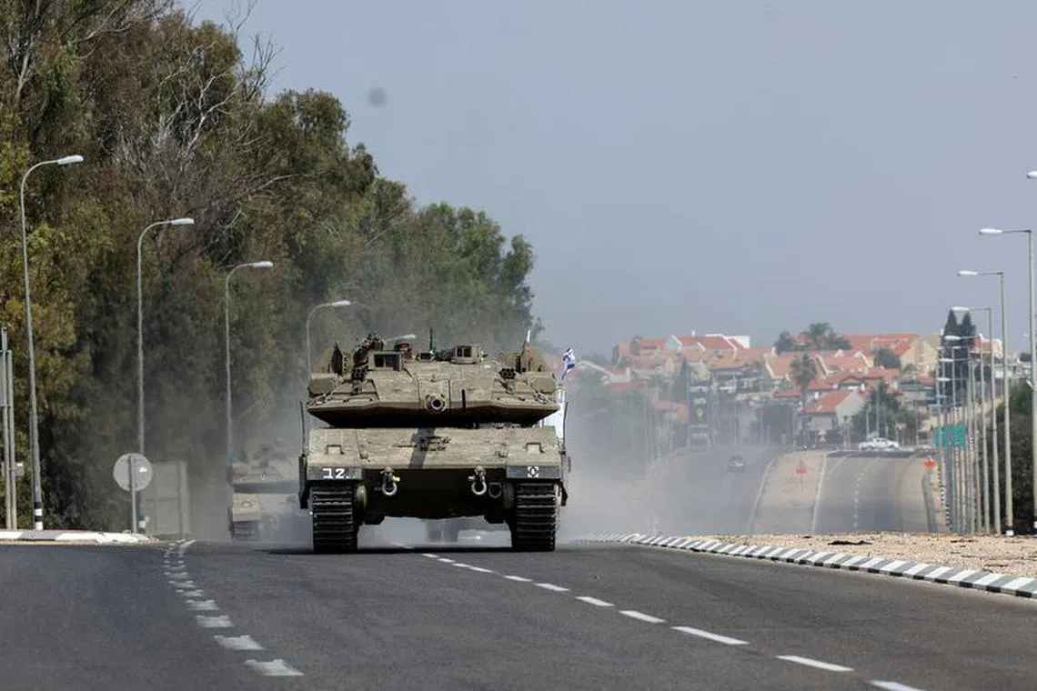 Israeli tanks drive on a road following a mass infiltration by Hamas gunmen from the Gaza Strip,  near Sderot in southern Israel October 8, 2023. REUTERS/Ronen Zvulun