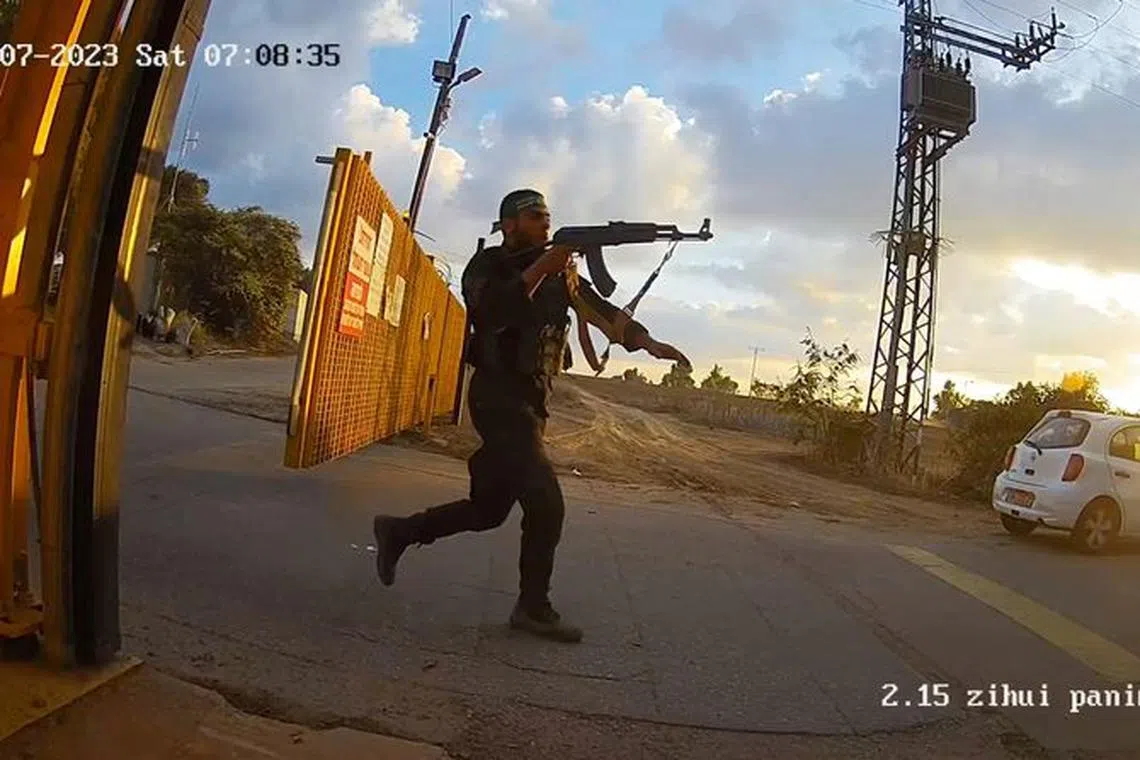 An armed man runs aiming his gun during the October 7 attack by Hamas, in this screen grab from footage captured by a surveillance camera in Kibbutz Alumim, Israel, and released November 20, 2023. South First Responders/Handout via REUTERS