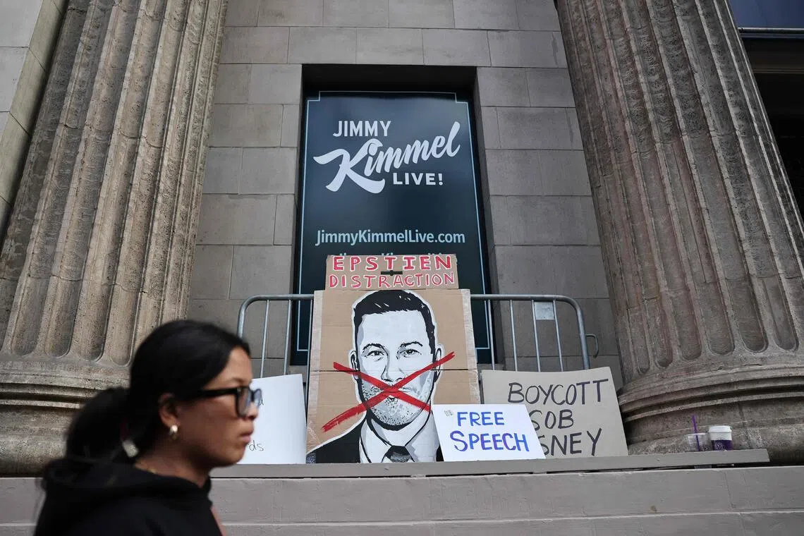 A pedestrian passes signs left by demonstrators protesting the suspension of the Jimmy Kimmel Live! show outside the El Capitan Entertainment Centre where the show is performed in Hollywood on September 18, 2025 in Los Angeles, California. 