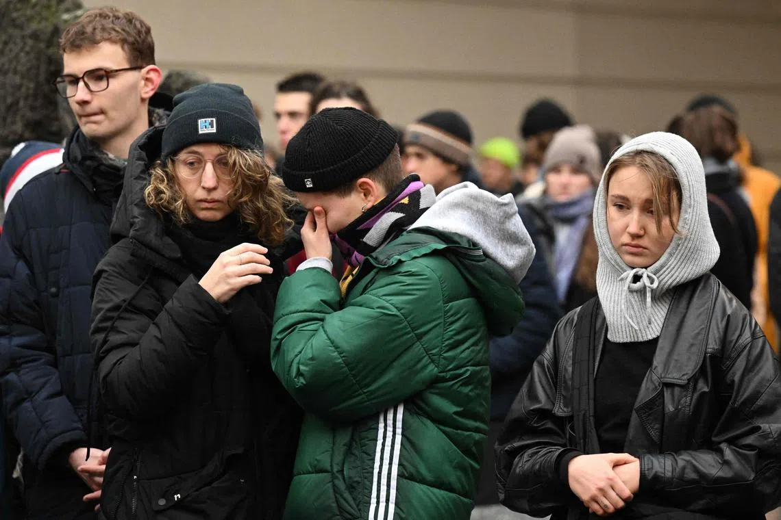 People mourn at a makeshift memorial for victims of the shooting, outside Charles University in central Prague.