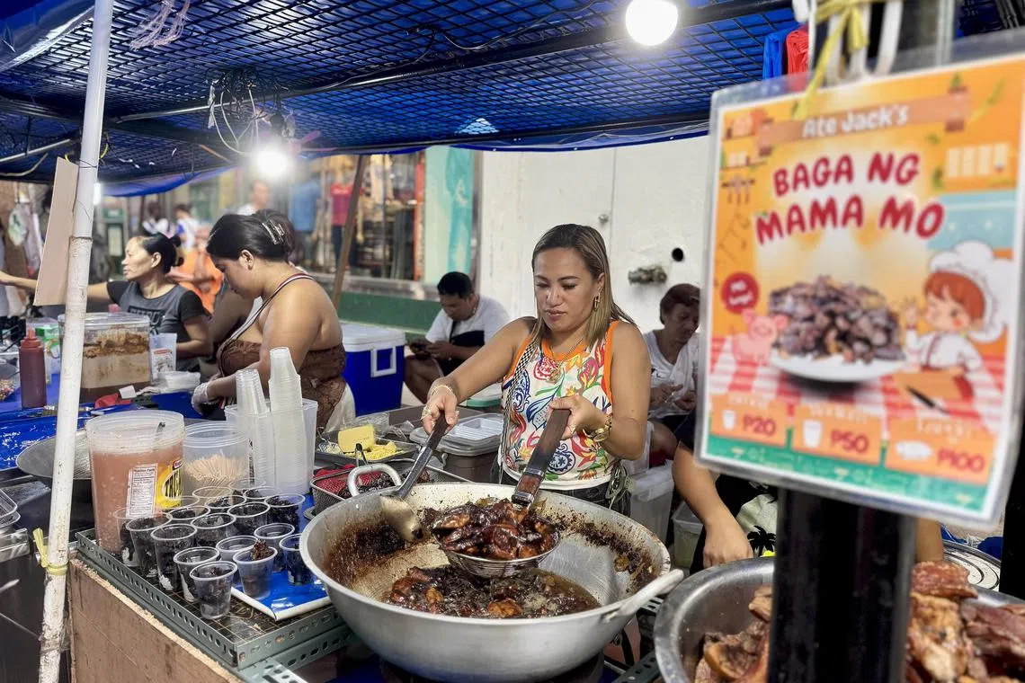 Street vendor Jacklyn Alfaro on July 31, 2025 cooks a fresh batch of fried pork lungs, the delicacy that made her stall famous along Carriedo Street in Manila, Philippines. 