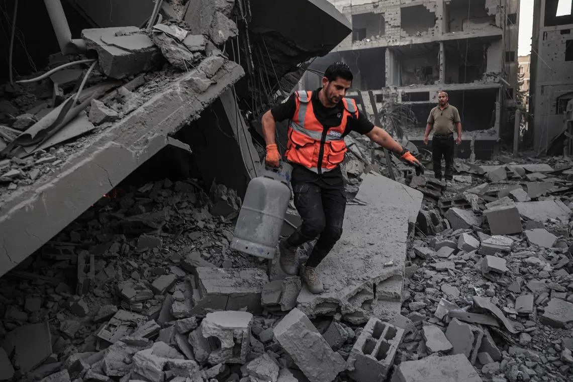 A rescuer salvages a gas canister from the rubble of a building, after it was hit by an Israeli strike in Rafah, in the southern Gaza Strip.