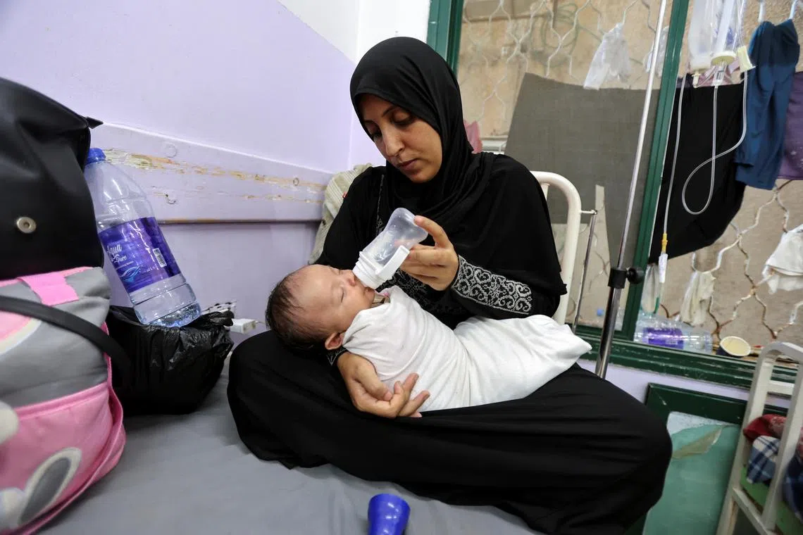 FILE PHOTO: A Palestinian woman bottle-feeds her baby girl at Al-Aqsa Martyrs Hospital, amid fears over the spread of polio after the first case was reported by the Ministry of Health, as the conflict between Israel and Hamas continues, in Deir Al-Balah in the central Gaza Strip, August 18, 2024. REUTERS/Ramadan Abed/File Photo