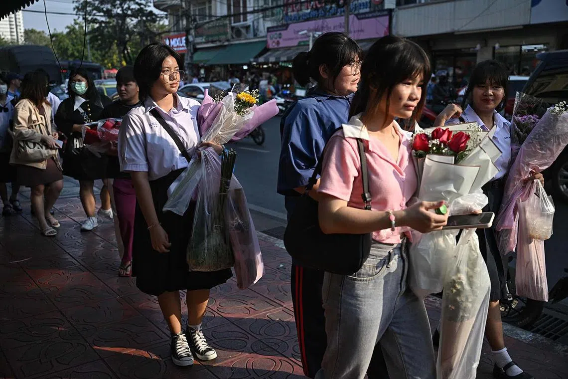 Students buying bouquets of flowers at Pak Khlong Talat flower market in Bangkok on Feb 13, 2024, on the eve of Valentine's Day. 