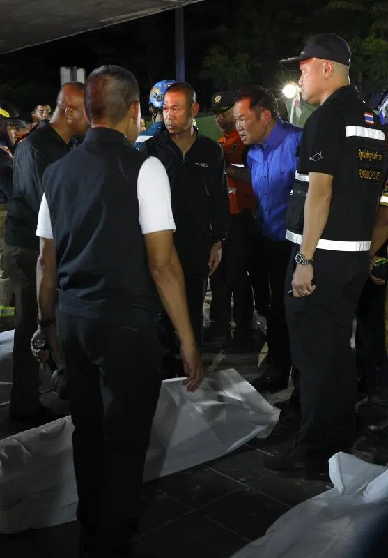 Thai Prime Minister Anutin Charnvirakul (second from right) inspecting the situation next to fire victims’ bodies outside the burned pub in Bangkok, early on July 13.