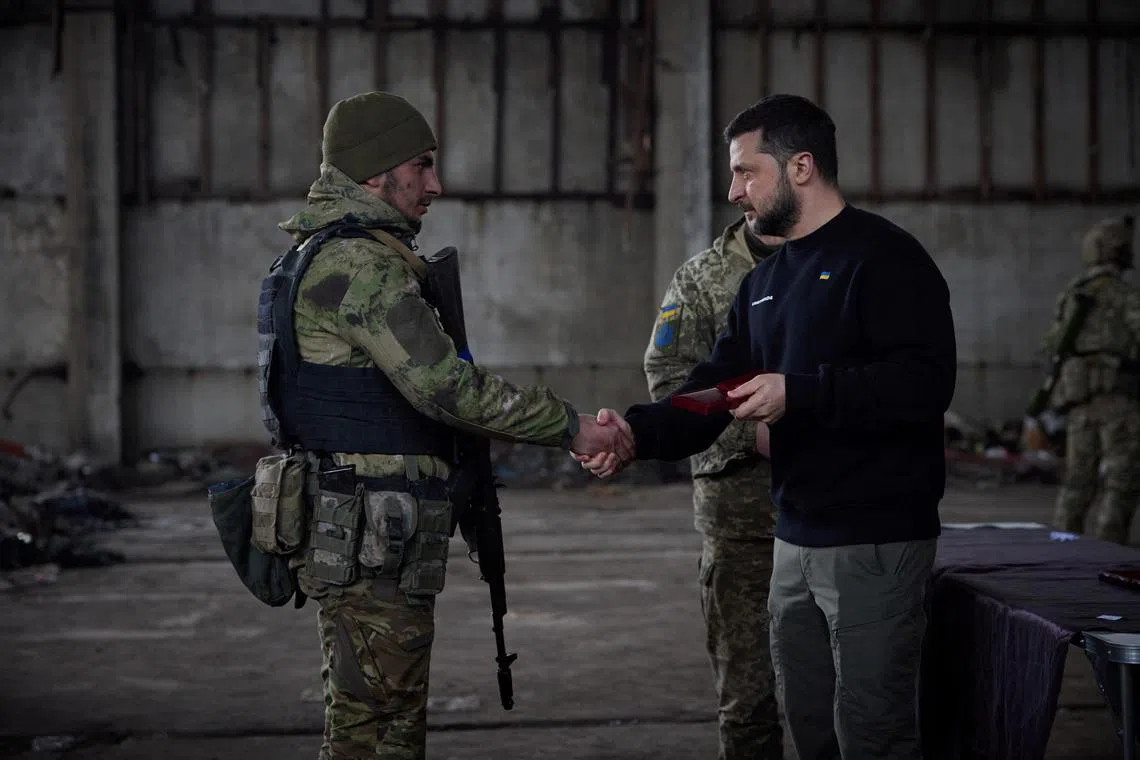 Ukraine's President Volodymyr Zelensky hands out a medal to a soldier on March 22, 2023. 