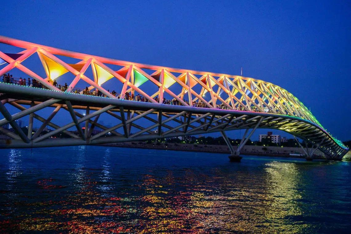 People walkingalong an illuminated pedestrian bridge over Sabarmati River in Ahmedabad on July 2.
