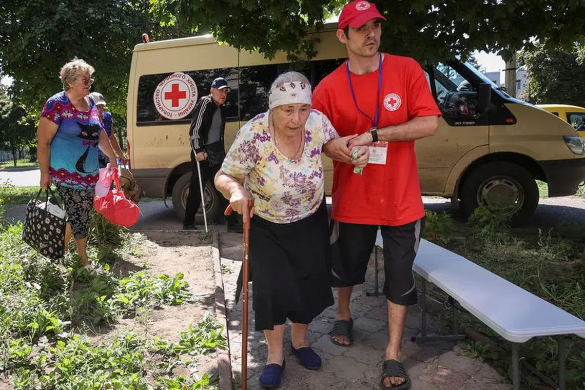 FILE PHOTO: A Red Cross volunteer helps an elderly woman to evacuate from the city of Kupiansk-Vuzlovyi in Kharkiv region, amid Russia's attack on Ukraine, in Kharkiv, Ukraine August 15, 2023. REUTERS/Vyacheslav Madiyevskyy/File Photo