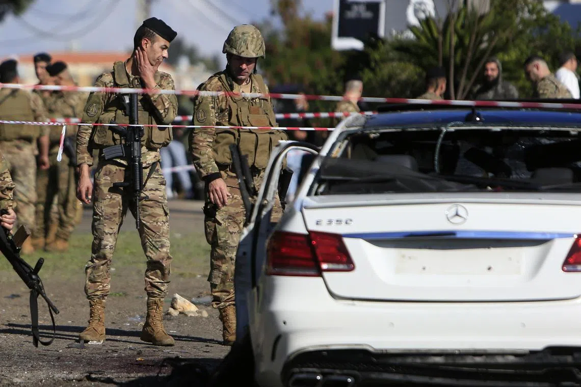 Lebanese army soldiers inspect a wrecked car, following a drone strike in the village of Jadra.