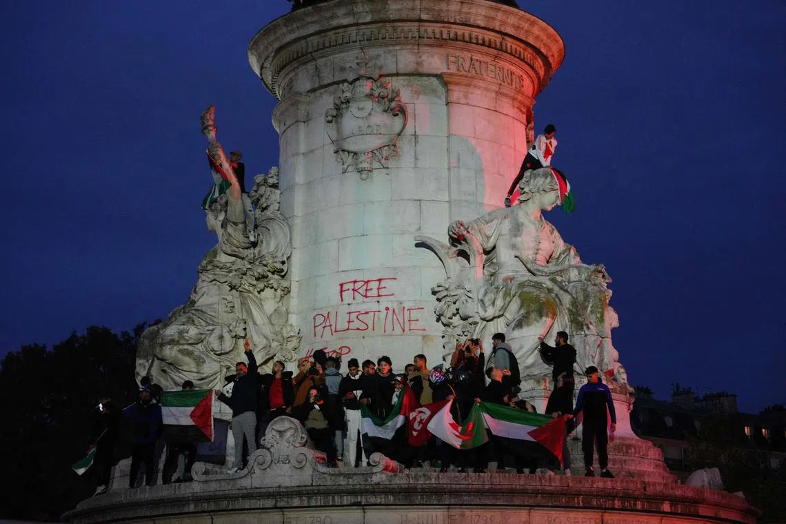 Protesters hold Palestinian flags as they stand on the Monument a la Republique during a demonstration in Paris.