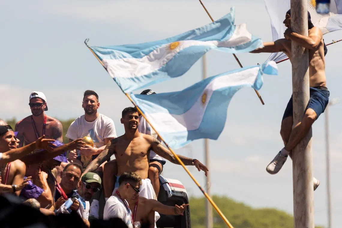 A fan of Argentina clinging to a pole cheers as the team passes by during their victory parade, Dec 20, 2022. 