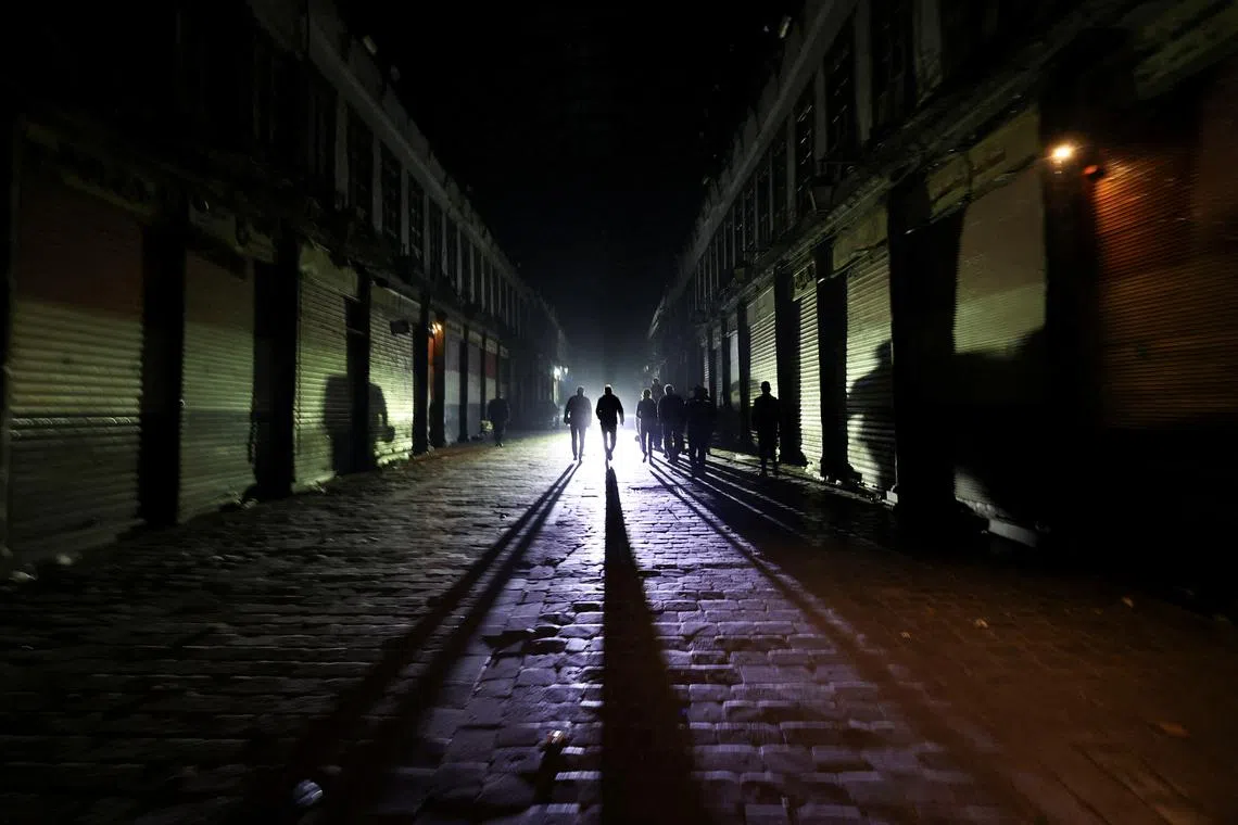 People walk next to closed shops during curfew, after Syrian rebels announced that they have ousted Syria's Bashar al-Assad, in Damascus, Syria December 9, 2024. REUTERS/Amr Abdallah Dalsh     TPX IMAGES OF THE DAY