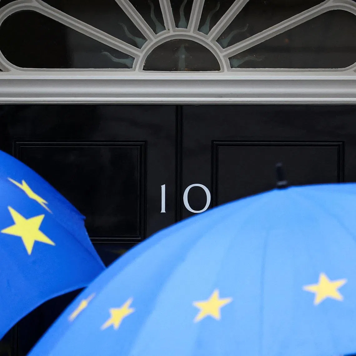 People shielding themselves from the rain with EU-themed umbrellas arrive at 10 Downing Street, in London, Britain, June 2, 2026. REUTERS/Toby Melville