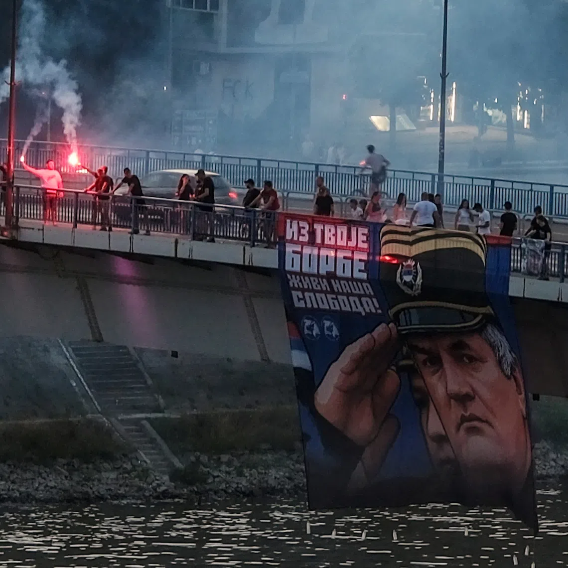 Supporters of the deceased Bosnian Serb general Ratko Mladic hold his picture and light flares on the Varadinski Bridge In Novi Sad Serbia, Serbia, August 27, 2026. REUTERS/Stefan Stojanovic