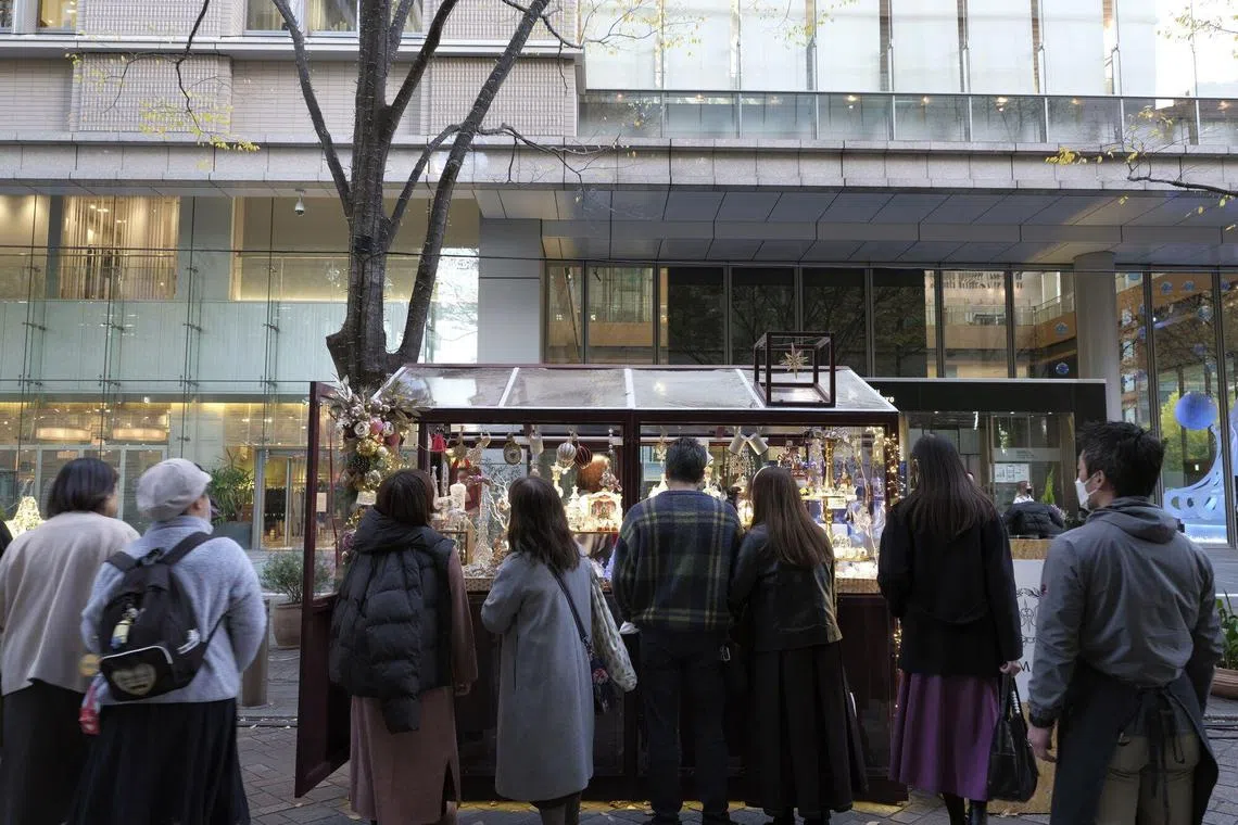 Shoppers browse at pop-up stores along a street decorated with Christmas lights, in the Marunouchi area of Tokyo, Japan.