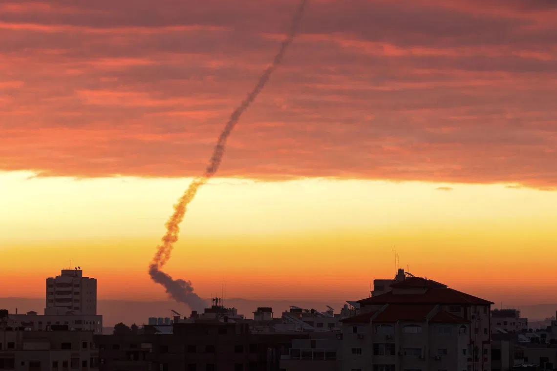TOPSHOT - Trails of smoke are seen as rockets are fired from Gaza towards Israel during the sunrise, in Gaza City on February 23, 2023. (Photo by MOHAMMED ABED / AFP)