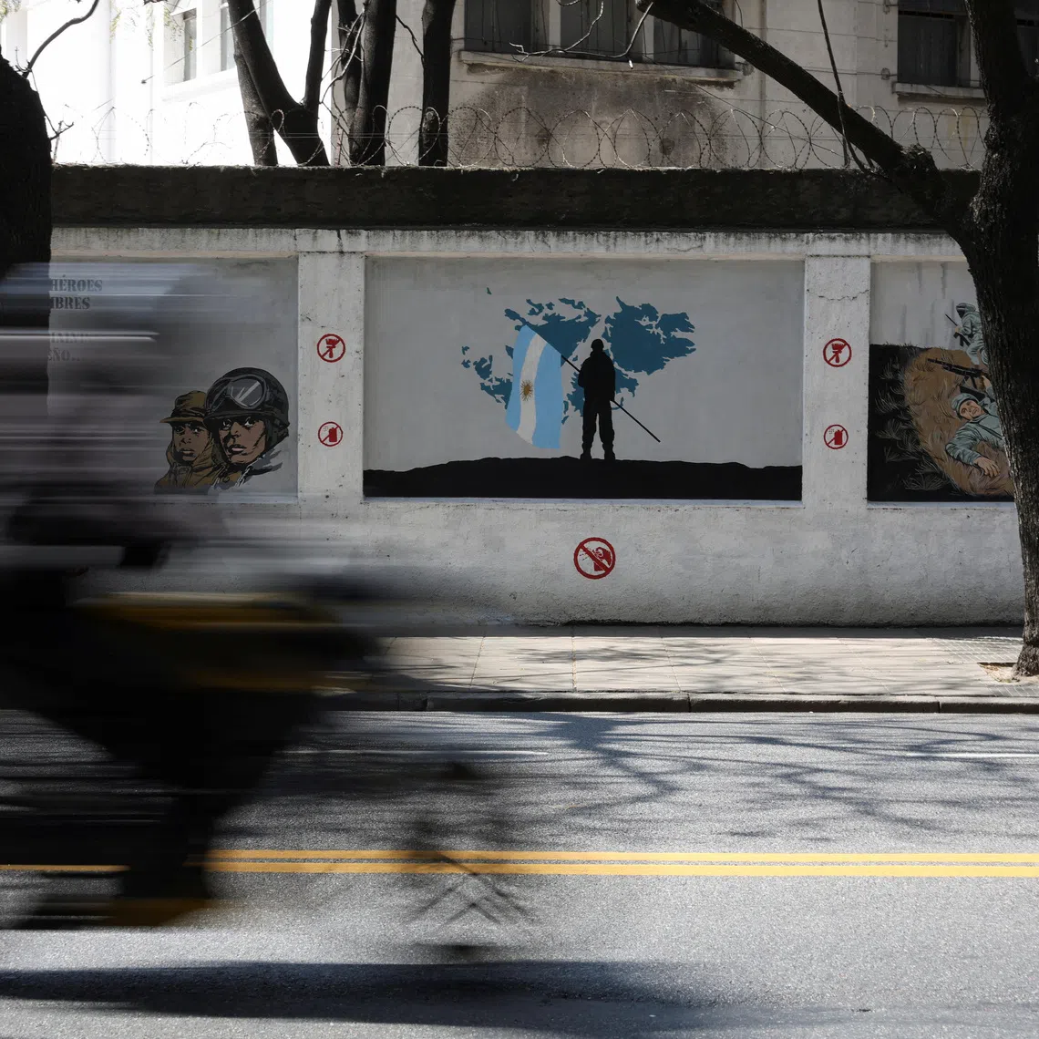 A motorcyclist rides past murals depicting soldiers and a map of the Falkland Islands, known in Argentina as the Islas Malvinas, commemorating the 1982 war between Britain and Argentina over the Falklands, in Buenos Aires, Argentina, September 15, 2026. REUTERS/Alessia Maccioni