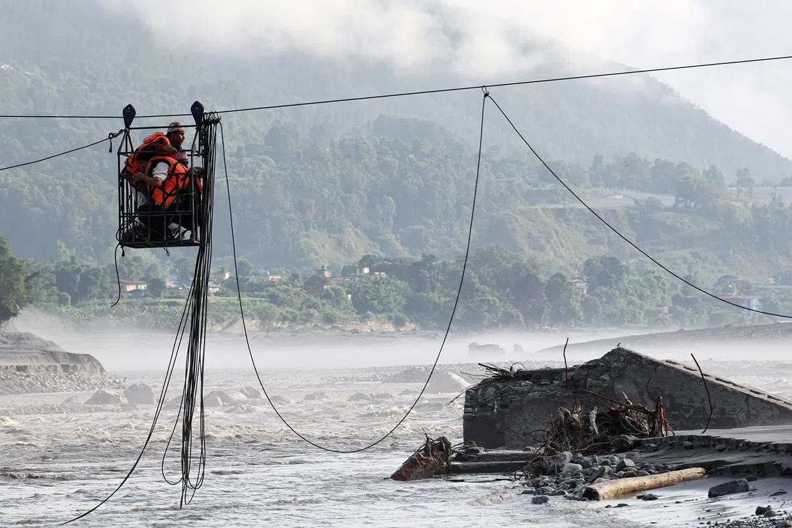 People hold onto a cage on a makeshift zipline as they cross the Trishuli River following deadly flash floods and a mudslide that damaged bridges and stranded residents, in Devighat, Nuwakot district, Nepal, September 9, 2026. REUTERS/Tyrone Siu TPX IMAGES OF THE DAY