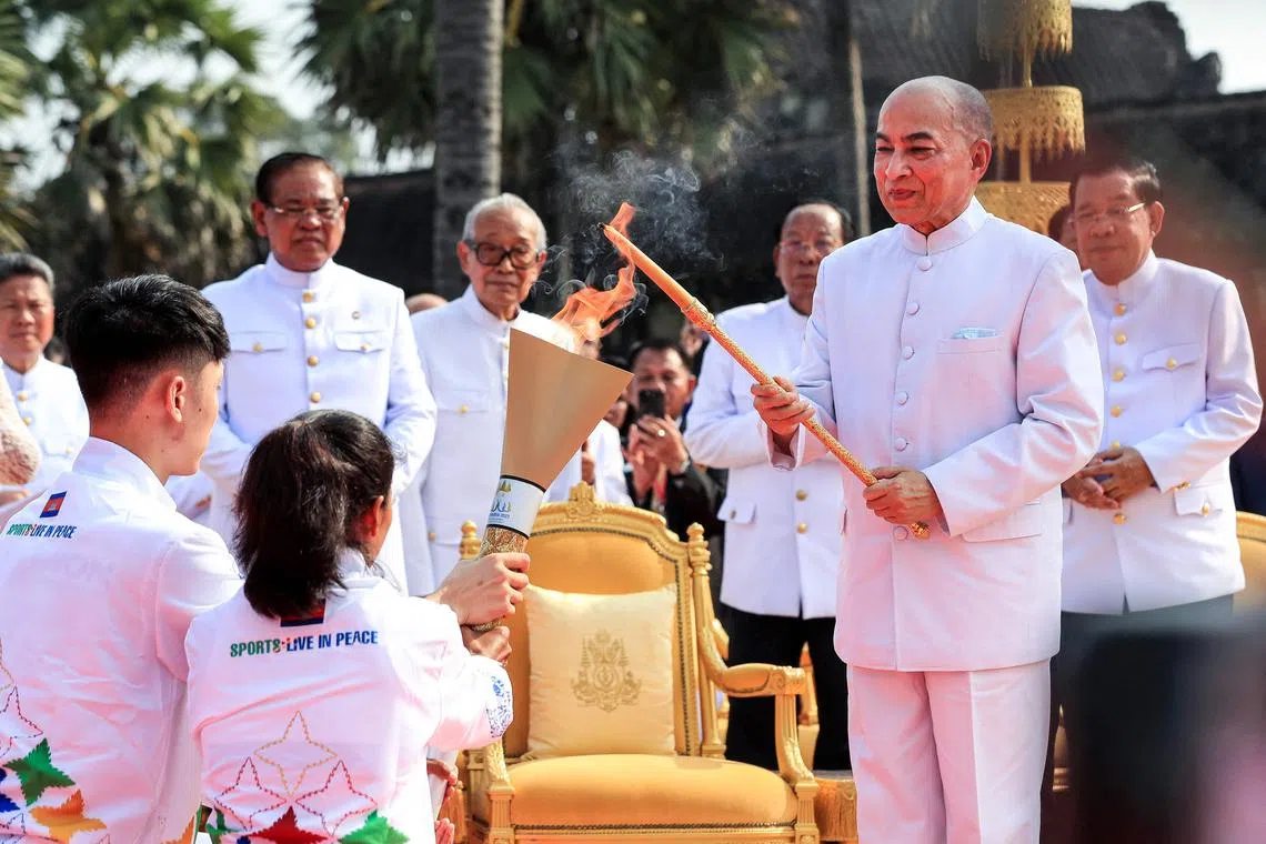 Cambodia's King Norodom Sihamoni (2nd R) lights the torch with a candle lit from the sun's rays as Prime Minister Hun Sen (R) looks on during a ceremony prior to the 32nd SEA Games at Angkor Wat temple in Siem Reap province on March 21, 2023. - The 2023 Southeast Asian Games (SEA Games) will be held from May 5 to 17 in Cambodia. (Photo by Ja Dina / AFP)