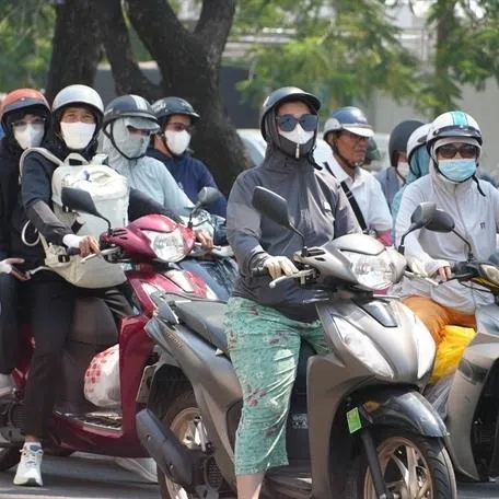 Motorbike riders in Hue City wear sun-protective gear as they travel along Tran Hung Dao Street amid the intense heatwave.