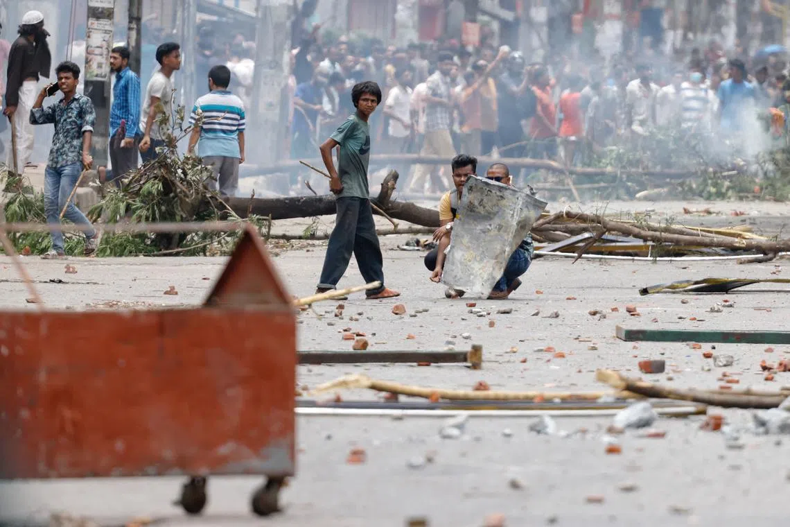 Protesters shield themselves with a metal sheet during a clash with Border Guard Bangladesh (BGB) and the police outside the state-owned Bangladesh Television as violence erupts across the country after anti-quota protests by students, in Dhaka, Bangladesh, July 19, 2024. REUTERS/Mohammad Ponir Hossain