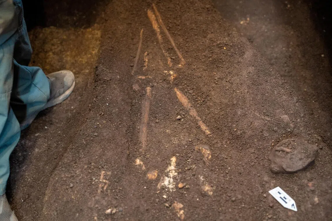 Archaeologists excavate and remove a pre-Hispanic burial, including human remains and associated artifacts such as a turtle-shaped Usulutan ceramic vessel, at the Pasaje 4 archaeological site in Antiguo Cuscatlan, El Salvador, on July 3.