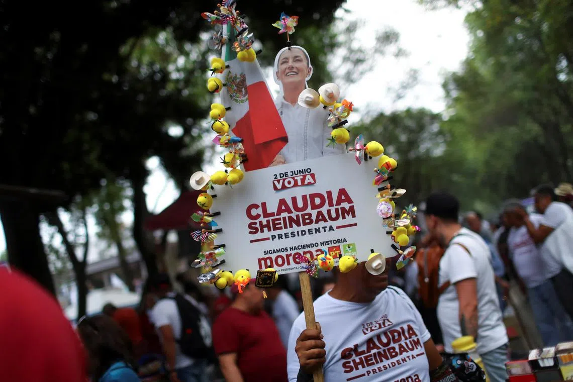A person holds up a placard with a cut-out of the presidential candidate of the ruling MORENA party Claudia Sheinbaum during her campaign rally in Mexico City, Mexico, May 22, 2024. REUTERS/Raquel Cunha/ File Photo