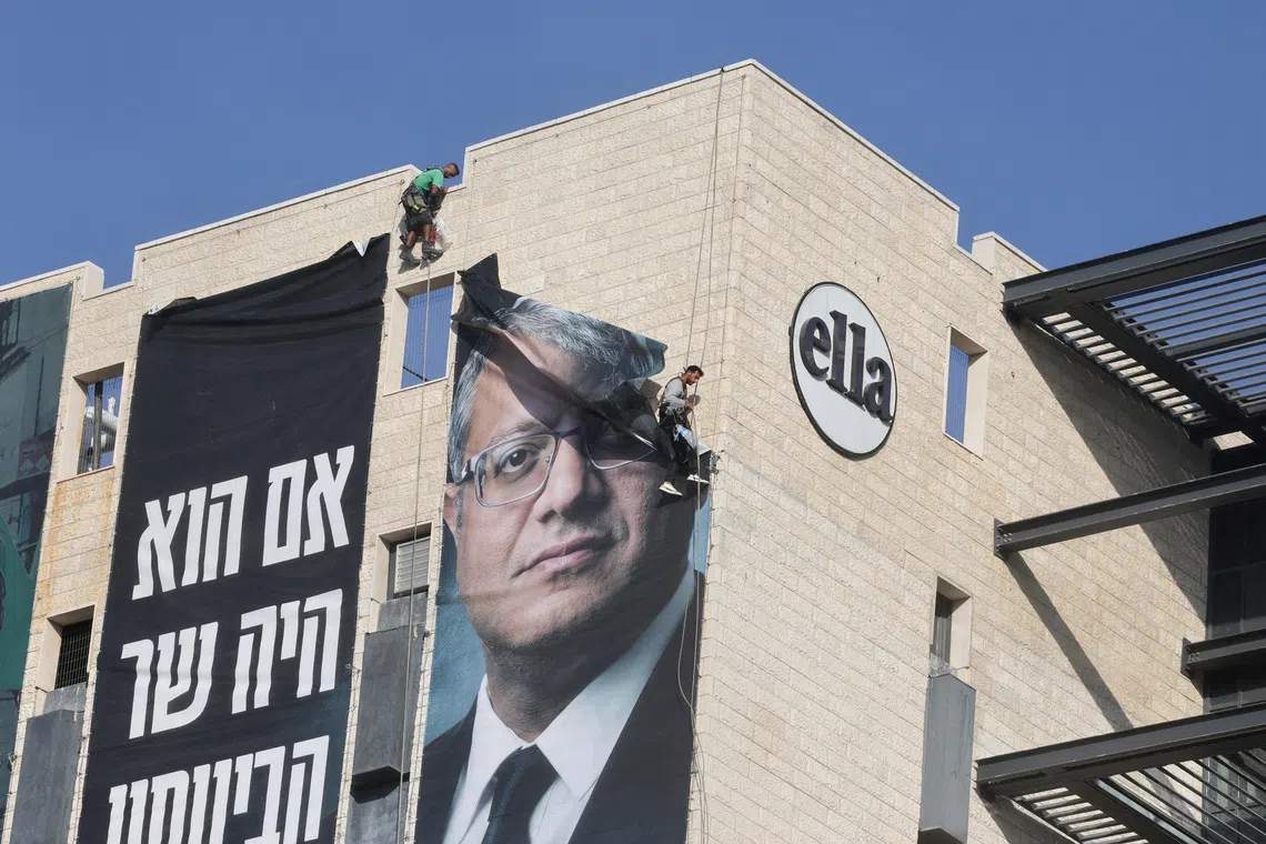Workers remove a banner featuring an image of Israel’s far-right National Security Minister Itamar Ben-Gvir, ahead of Israel’s general election.