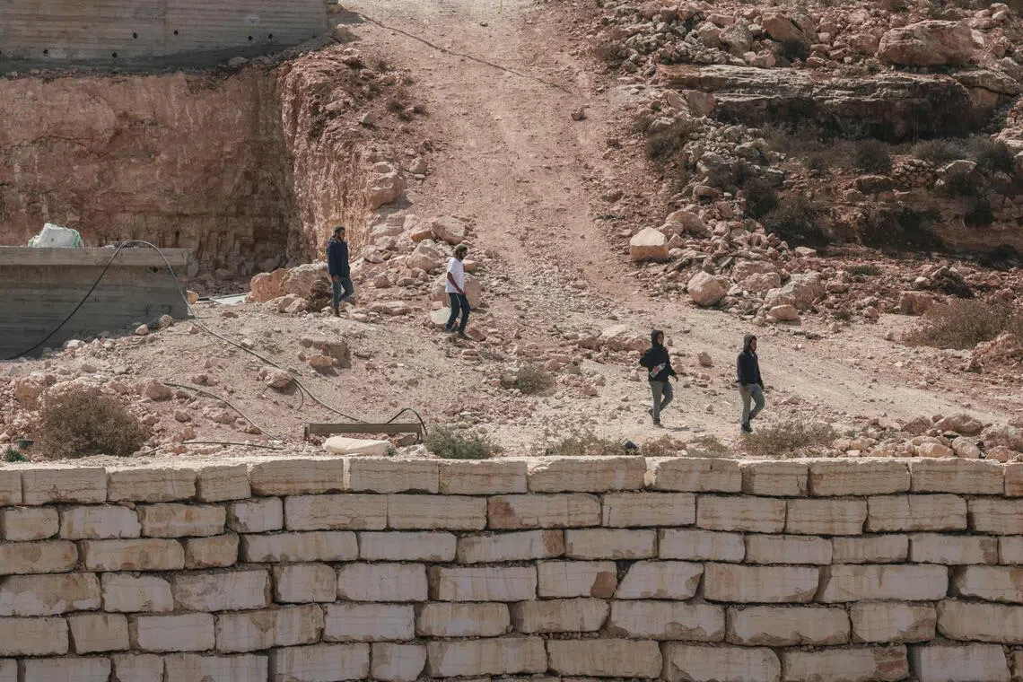Israeli settlers walks towards a Palestinian home under construction in the village of Qusra, in the Israeli-occupied West Bank, which has faced escalating settler violence over the past month.