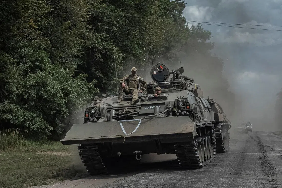 Ukrainian soldiers ride an armoured vehicle as they push towards Russia near the border the in Sumy region
