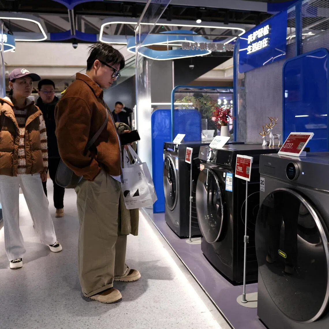 FILE PHOTO: Customers shop for a washing machine at a home appliance mall in Beijing, China October 19, 2025. REUTERS/Tingshu Wang/File Photo