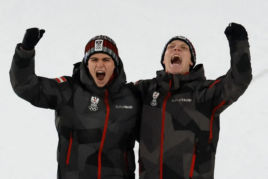 Milano Cortina 2026 Olympics - Ski Jumping - Men's Super Team Victory Ceremony - Predazzo Ski Jumping Stadium, Predazzo, Italy - February 16, 2026. Gold medallist's Jan Hoerl of Austria and Stephan Embacher of Austria celebrate on the podium during the men's super team victory ceremony REUTERS/Stephanie Lecocq