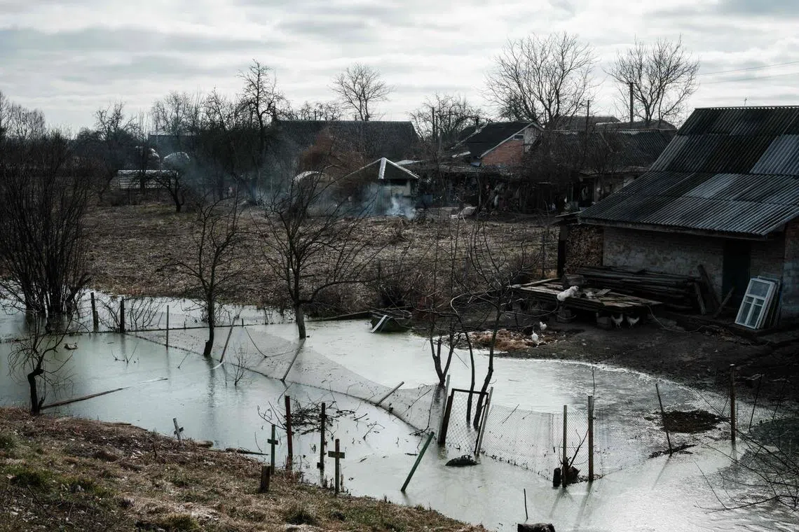 The abandoned gardens at the homes of Valentina Ossipova, 77, and Ivan Kukuruza, 69, remain water-logged after being flooded a year ago in Demydiv, 35 kilometers north of Kyiv, on February 28, 2023. - Within the first hours of Russia's invasion of Ukraine on February 25, 2022, the Ukrainian armed forces blew the Irpin river barrage, upriver to slow Russian advances by flooding the surrounding area, turning it into a swampy quagmire. A year on, the town of Demydiv (alternatively spelled "Demidov") is reeling from the flood that struck over 60 houses in the area. (Photo by YASUYOSHI CHIBA / AFP)