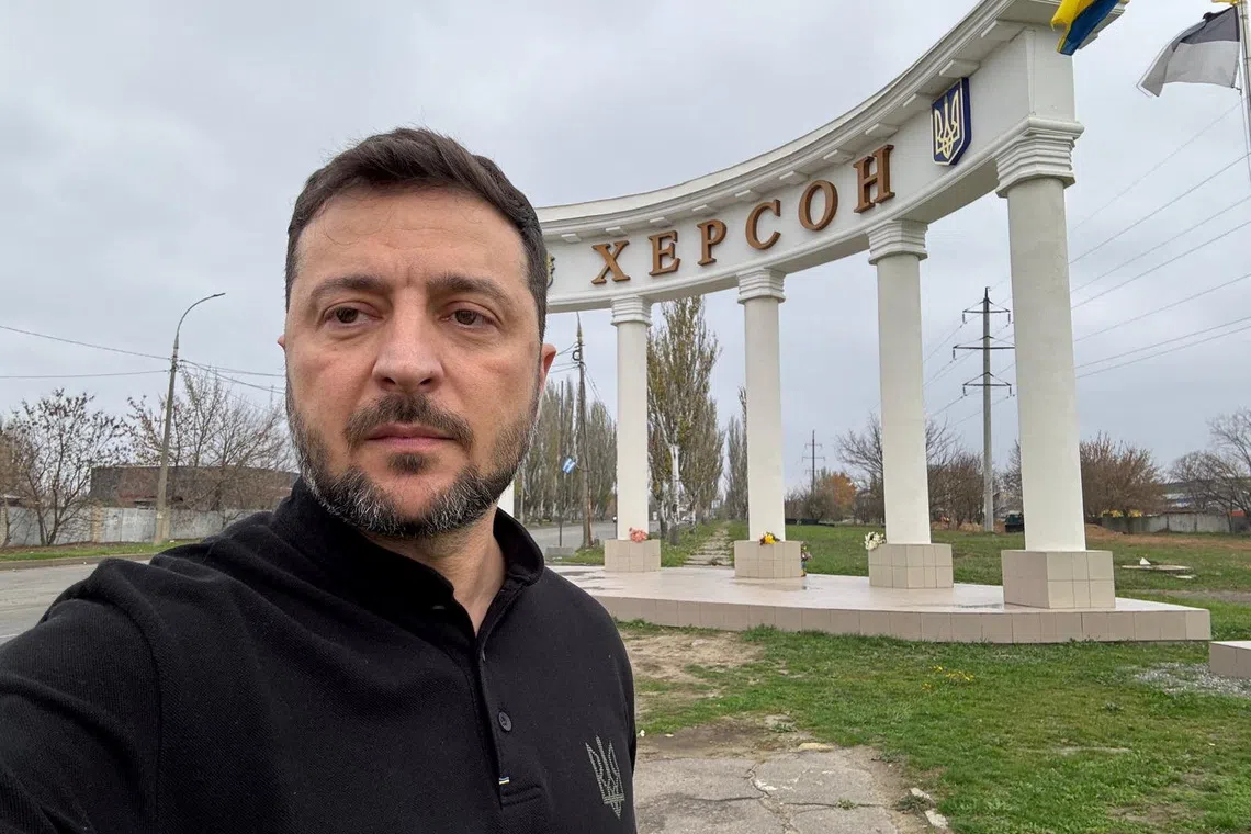 Ukraine's President Volodymyr Zelenskiy takes a selfie in front of the Kherson city entrance, during his visit to the city, amid Russia's attack on Ukraine, November 11, 2025. Ukrainian Presidential Press Service/Handout via REUTERS