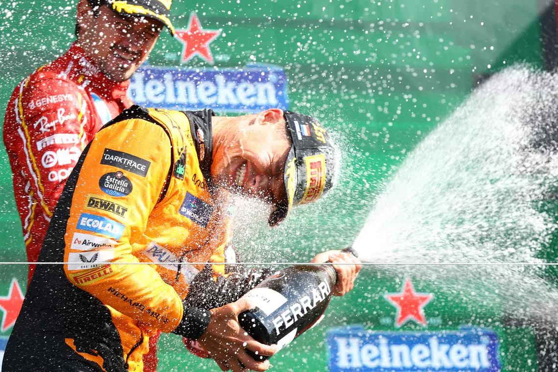 Formula One F1 - Dutch Grand Prix - Circuit Zandvoort, Zandvoort, Netherlands - August 25, 2024 McLaren's Lando Norris celebrates with champagne on the podium after winning the Dutch Grand Prix with third placed Ferrari's Charles Leclerc REUTERS/Lisi Niesner