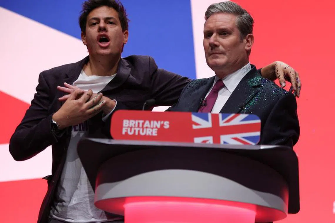 A protester stands next to Britain's Labour Party Leader Keir Starmer at Britain's Labour Party annual conference in Liverpool, Britain, October 10, 2023. REUTERS/Phil Noble