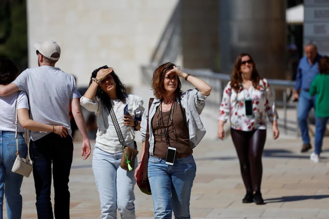 Women shade their eyes during hot weather in Bilbao, Spain, April 13, 2024. REUTERS/Vincent West