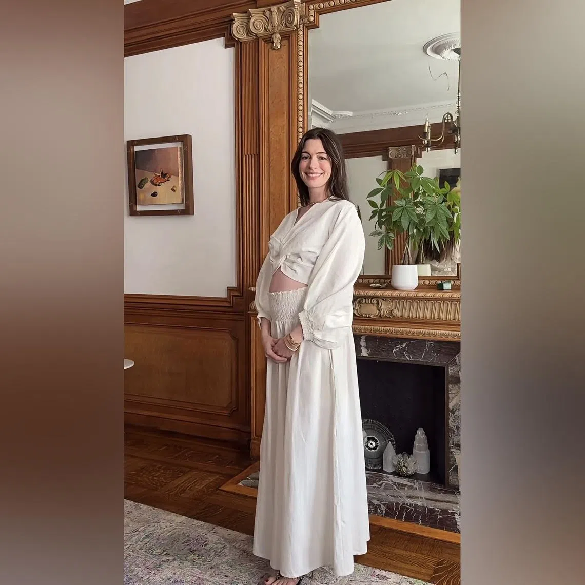 Anne Hathaway shared a video on her Instagram account of her stepping into frame and cradling her baby bump in a white flowy outfit as she smiled.