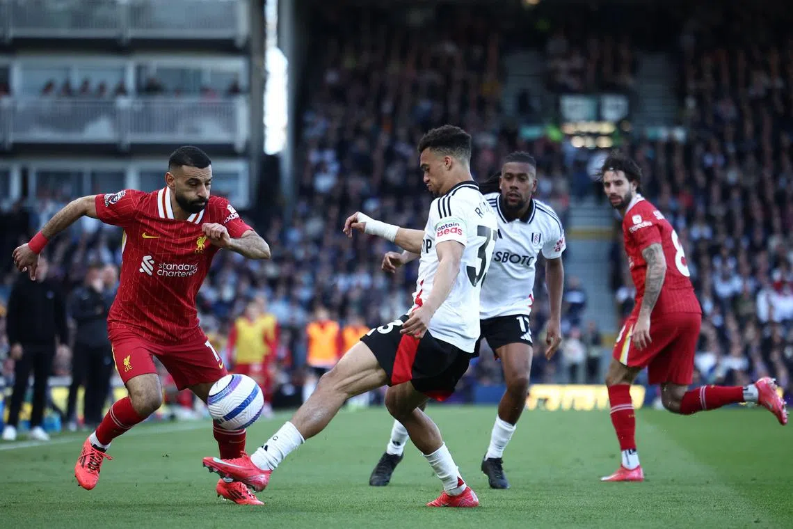 Liverpool's Egyptian striker #11 Mohamed Salah (L) vies with Fulham's English-born US defender #33 Antonee Robinson (C) during the English Premier League football match between Fulham and Liverpool at Craven Cottage in London on April 6, 2025. (Photo by HENRY NICHOLLS / AFP) / RESTRICTED TO EDITORIAL USE. No use with unauthorized audio, video, data, fixture lists, club/league logos or 'live' services. Online in-match use limited to 120 images. An additional 40 images may be used in extra time. No video emulation. Social media in-match use limited to 120 images. An additional 40 images may be used in extra time. No use in betting publications, games or single club/league/player publications. / 