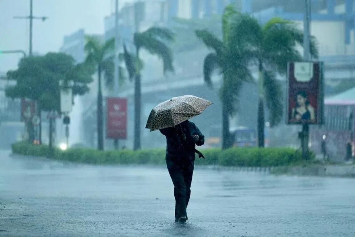 A man holds an umbrella as he walks along a street amid heavy rains ahead of a cyclonic storm in Chennai on November 30, 2024. (Photo by R.Satish BABU / AFP)